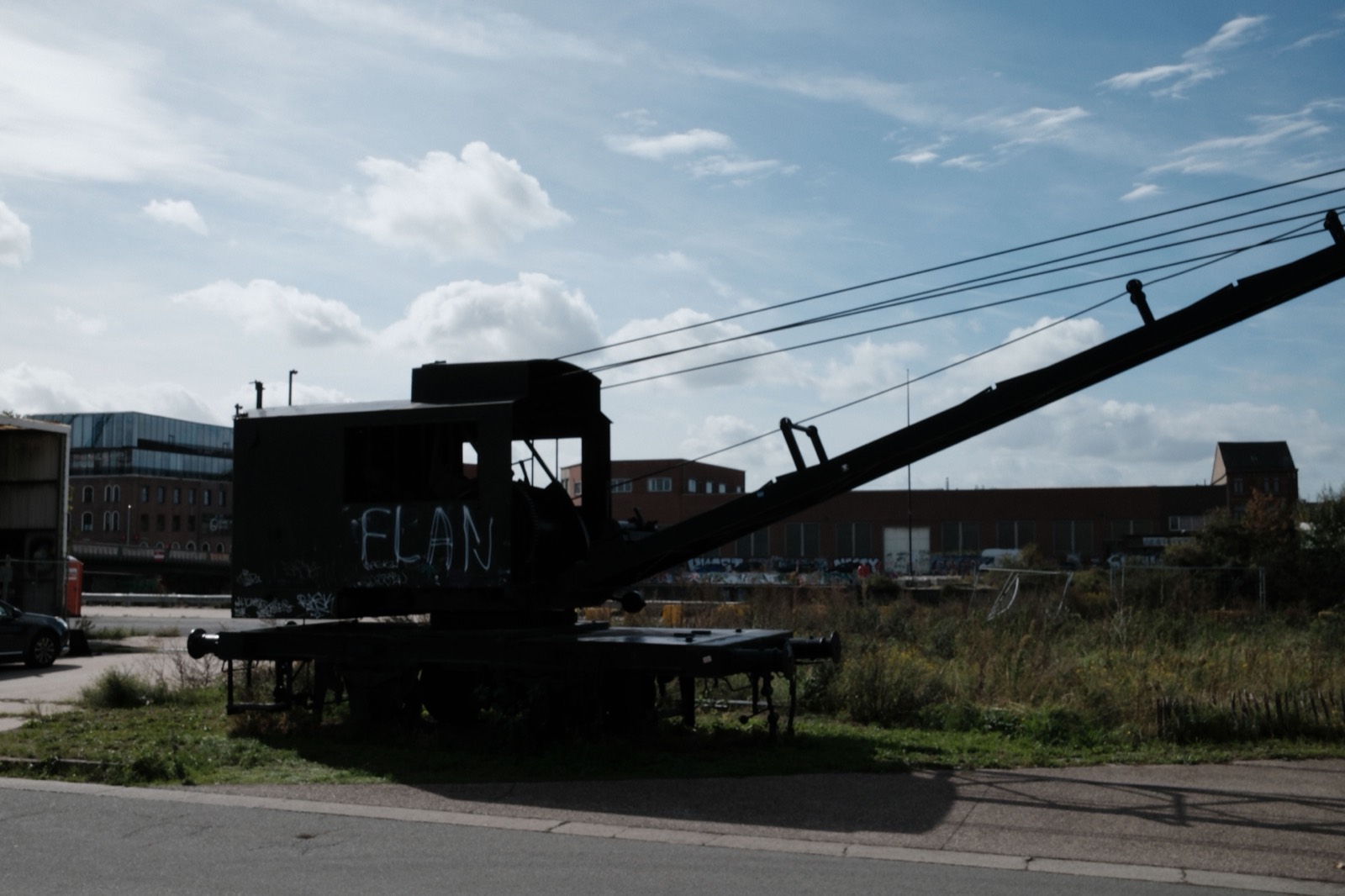 Silhouet van een oude kraan met het woord ELAN erop, tegen een bewolkte lucht