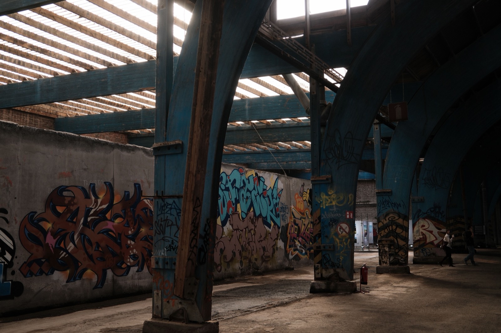 Oude staalhal met blauwe stalen bogen en graffiti op de muren