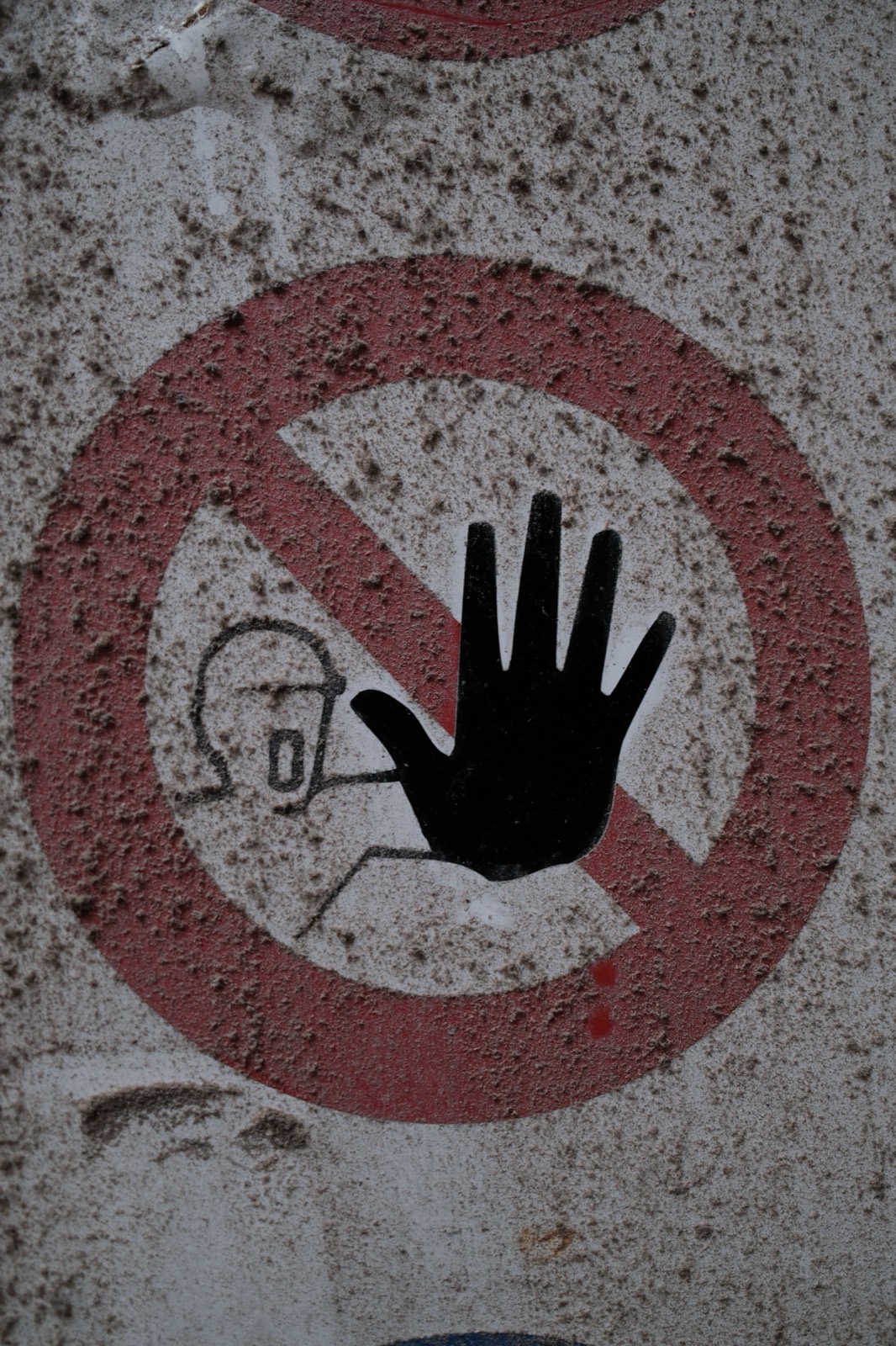 Rood bord met een zwarte hand: verboden toegang, op een verweerde muur